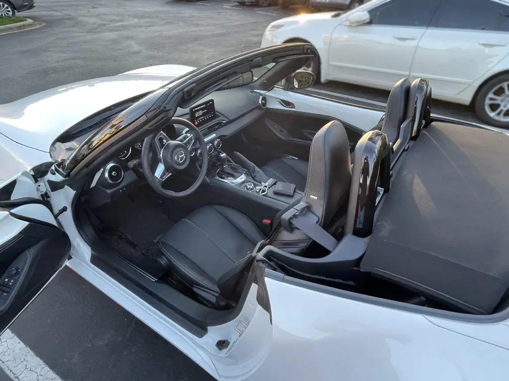 Picture of the Miata with the top down in a parking lot